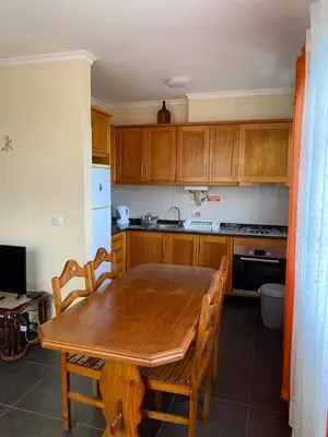 a kitchen with a wooden table and wooden cabinets at Ocean Guest House in São Vicente