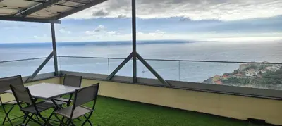 a balcony with a table and chairs and the ocean at Paraíso Pico da Torre in Câmara de Lobos