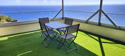 two chairs and a table on a balcony with the ocean at Paraíso Pico da Torre in Câmara de Lobos