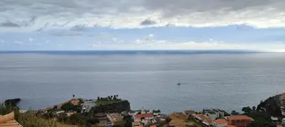 a view of a large body of water with a boat at Paraíso Pico da Torre in Câmara de Lobos
