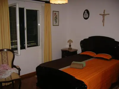 a bedroom with a bed and a cross on the wall at Residencia ANA Piso Um 1 in Santa Cruz