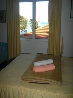 a bed with two towels on a wooden tray with a window at Residencia ANA Piso Um 1 in Santa Cruz