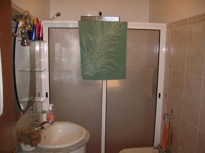a bathroom with a sink and a shower with a green towel at Residencia ANA Piso Um 1 in Santa Cruz