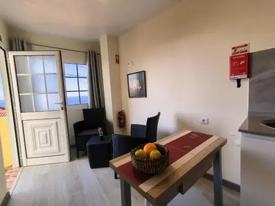 a small living room with a chair and a kitchen at O Cantinho do André in Porto Moniz