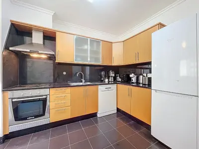 a kitchen with wooden cabinets and a table with chairs at Agostinho Apartment by Atlantic Holiday in Santa Cruz