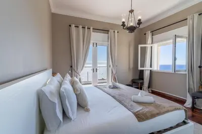 a bedroom with a large white bed with windows at Só Espeto Accommodation Rooms in Santa Cruz