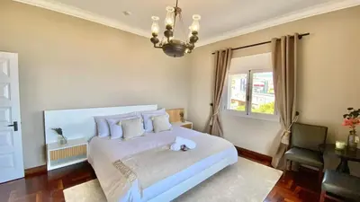 a bedroom with a large white bed and a chandelier at Só Espeto Accommodation Rooms in Santa Cruz
