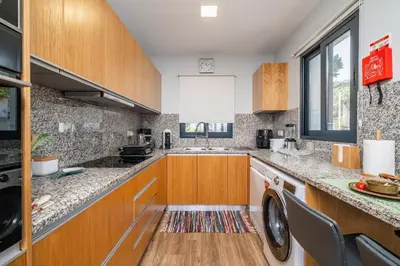 a kitchen with wooden cabinets and a washer and dryer at Salsa Country House II in Porto Moniz