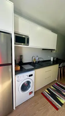 a kitchen with a washing machine and a microwave at Anastacio Tiny House in Porto Moniz