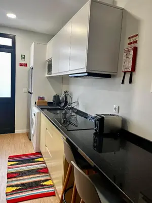 a kitchen with white cabinets and a black counter top at Anastacio Tiny House in Porto Moniz