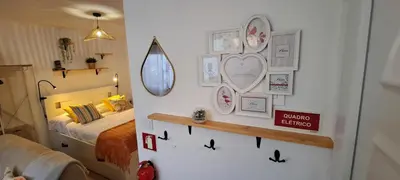 a bedroom with a bed and a white wall with pictures at Cozy Studio - Chalé Seixal in Seixal