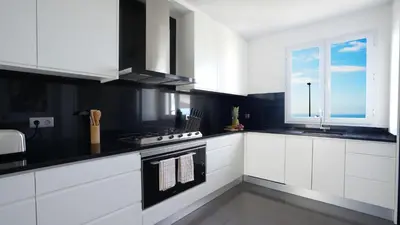 a white kitchen with a stove and a window at NostraCasa by LovelyStay in Caniço