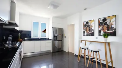 a kitchen with white cabinets and a counter with stools at NostraCasa by LovelyStay in Caniço