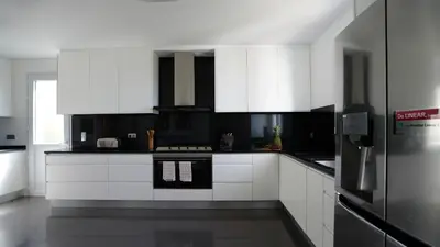 a white kitchen with white cabinets and a refrigerator at NostraCasa by LovelyStay in Caniço
