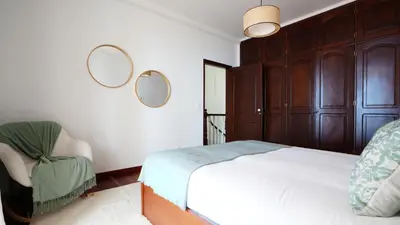 a bedroom with a bed and a chair and two mirrors at NostraCasa by LovelyStay in Caniço