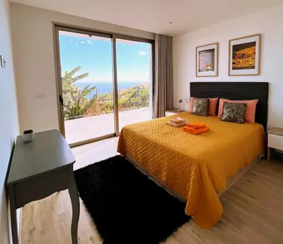a bedroom with a bed and a large window at Holiday House Caetano in Ponta do Sol