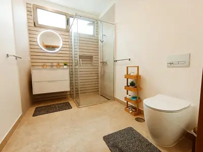 a bathroom with a glass shower and a toilet at Holiday House Caetano in Ponta do Sol