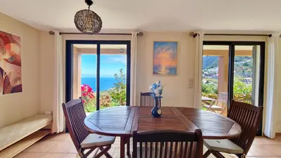 a dining room with a table and chairs and windows at Garden of Eden by LovelyStay in Ponta Delgada