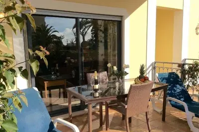 a glass table and chairs on a balcony with a table and a window at Casa Ella in Lagos