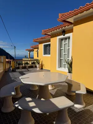 a patio with a table and benches in front of a house at Casa Gonçalves in São Vicente