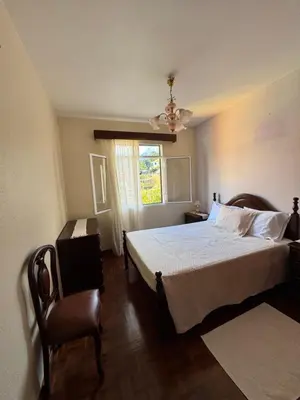 a bedroom with a bed and a chair and a window at Casa Gonçalves in São Vicente