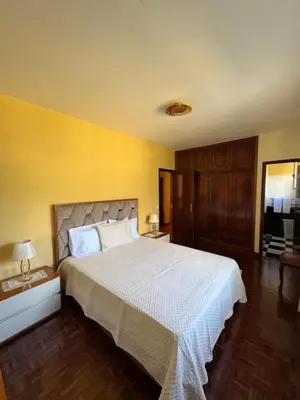 a bedroom with a large bed and a yellow wall at Casa Gonçalves in São Vicente