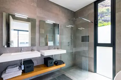 a bathroom with two sinks and a glass shower at CasaMar in Jardim do Mar