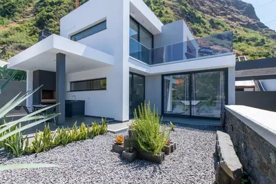 a white house with a mountain in the background at CasaMar in Jardim do Mar