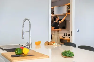 a woman in a kitchen preparing food in a cabinet at Bayview Villa Retreat in Funchal