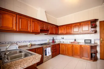 a kitchen with wooden cabinets and a sink at Levada House Prazeres in Prazeres