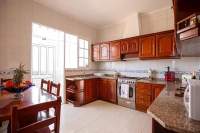 a kitchen with wooden cabinets and a table with a bowl of fruit at Levada House Prazeres in Prazeres