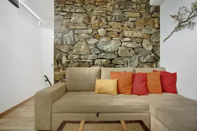 a couch in a room with a stone wall at Host Albina in Funchal