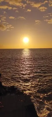 a sunset over the ocean with a boat in the water at Host Albina in Funchal