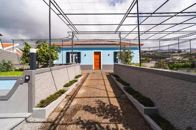 a blue building with a red door and a walkway at Luxury Retreat in Camara de Lobos in Câmara de Lobos