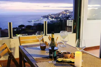 a table with wine glasses and a view of the city at Funchal Sunset Apartment in Funchal