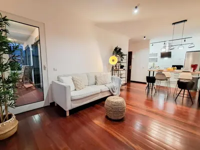 a living room with a white couch and a kitchen at Funchal Sunset Apartment in Funchal