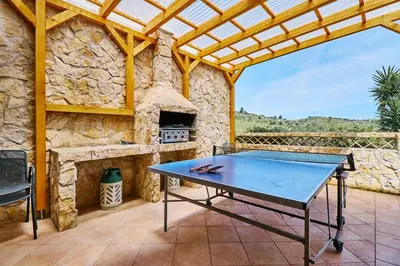 a ping pong table on a patio with a stone wall at Lovely hugh villa close to beaches up to 10 sleeps in Hortas do Tabual