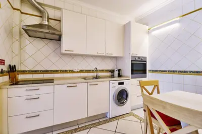 a kitchen with white cabinets and a washing machine at Lovely hugh villa close to beaches up to 10 sleeps in Hortas do Tabual