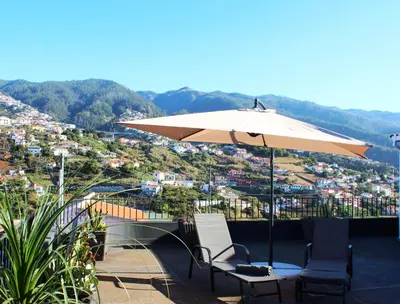 a table and chairs under an umbrella on a balcony at Madeira Home Spacious Accommodation in Funchal