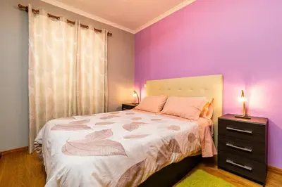 a bedroom with a large bed with purple walls at Green Doors - AC and free parking in Machico