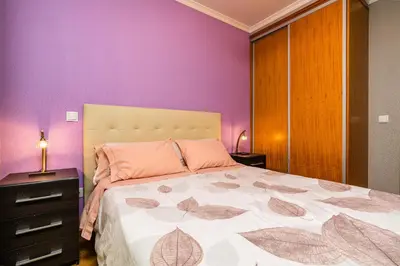 a bedroom with purple walls and a bed with two lamps at Green Doors - AC and free parking in Machico