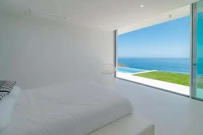 a bedroom with a white bed and a large window at Villa Gia in Calheta