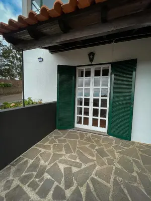 a house with green doors and a stone patio at Estalagem Estrela in Estrela
