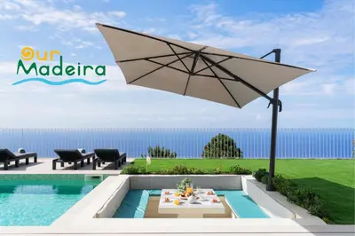 a patio with an umbrella next to a pool at OurMadeira - Villa Adagio in Estreito da Calheta