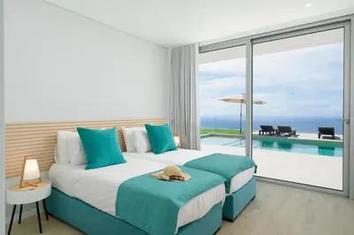 a bedroom with a bed and a view of the ocean at OurMadeira - Villa Adagio in Estreito da Calheta