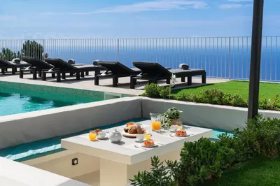 a table with food on it next to a pool at OurMadeira - Villa Adagio in Estreito da Calheta