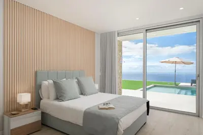 a bedroom with a bed and a view of the ocean at OurMadeira - Villa Adagio in Estreito da Calheta