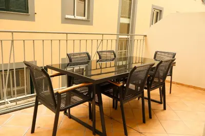 a glass table and chairs on a balcony at Suites Do Carmo in Funchal