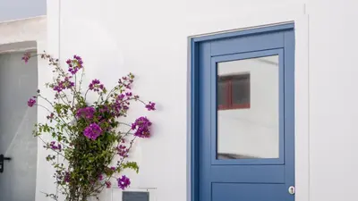 a blue door with a plant with purple flowers at Stylish Slow Living 1 BDR House by LovelyStay in Vila do Bispo