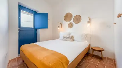 a small bedroom with a blue door and a bed at Stylish Slow Living 1 BDR House by LovelyStay in Vila do Bispo